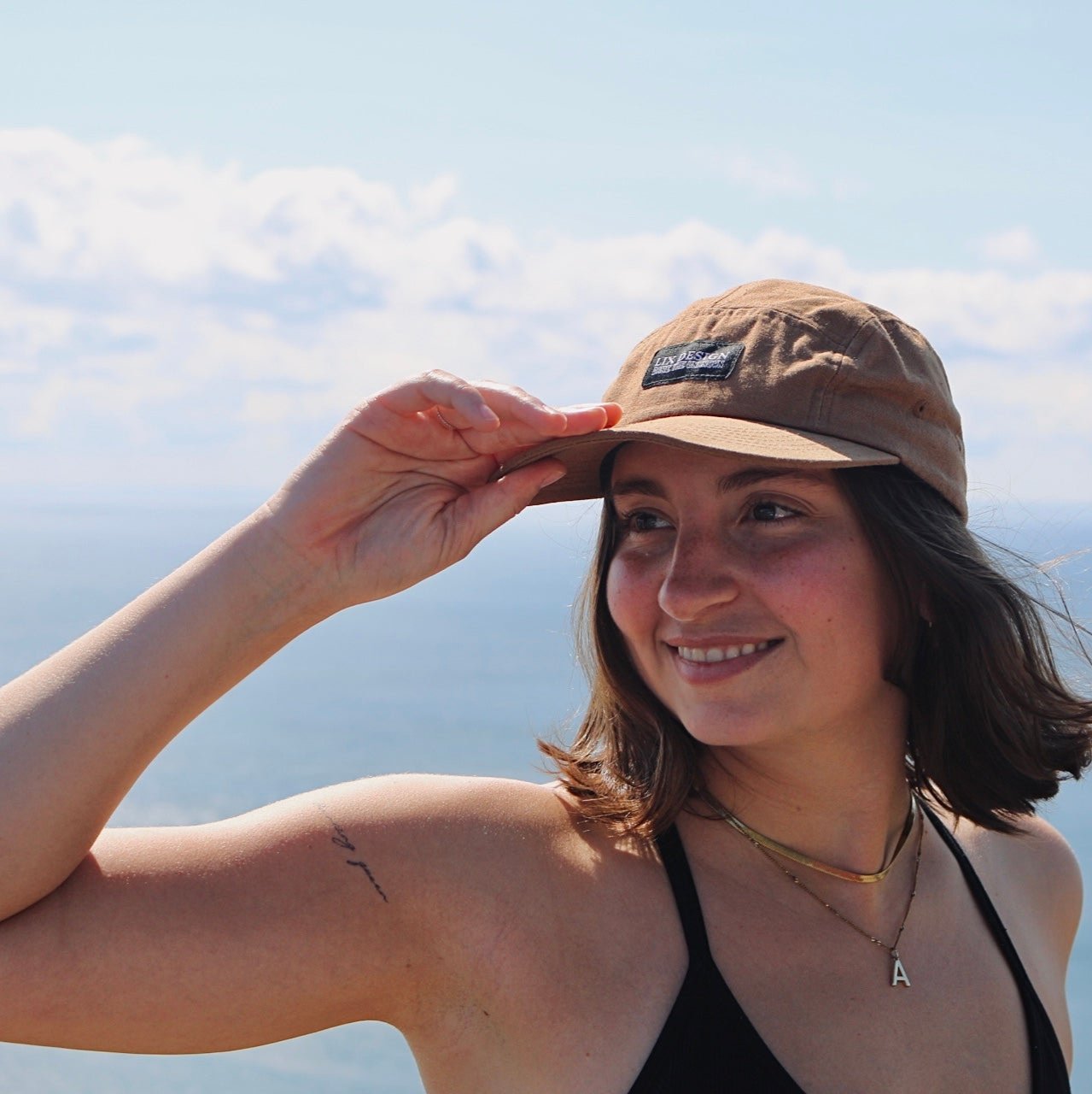 Casquette brune avec étiquette noir. Casquette à 5 panneaux avec visière droite pouvant être courbé.  Casquette de trek.