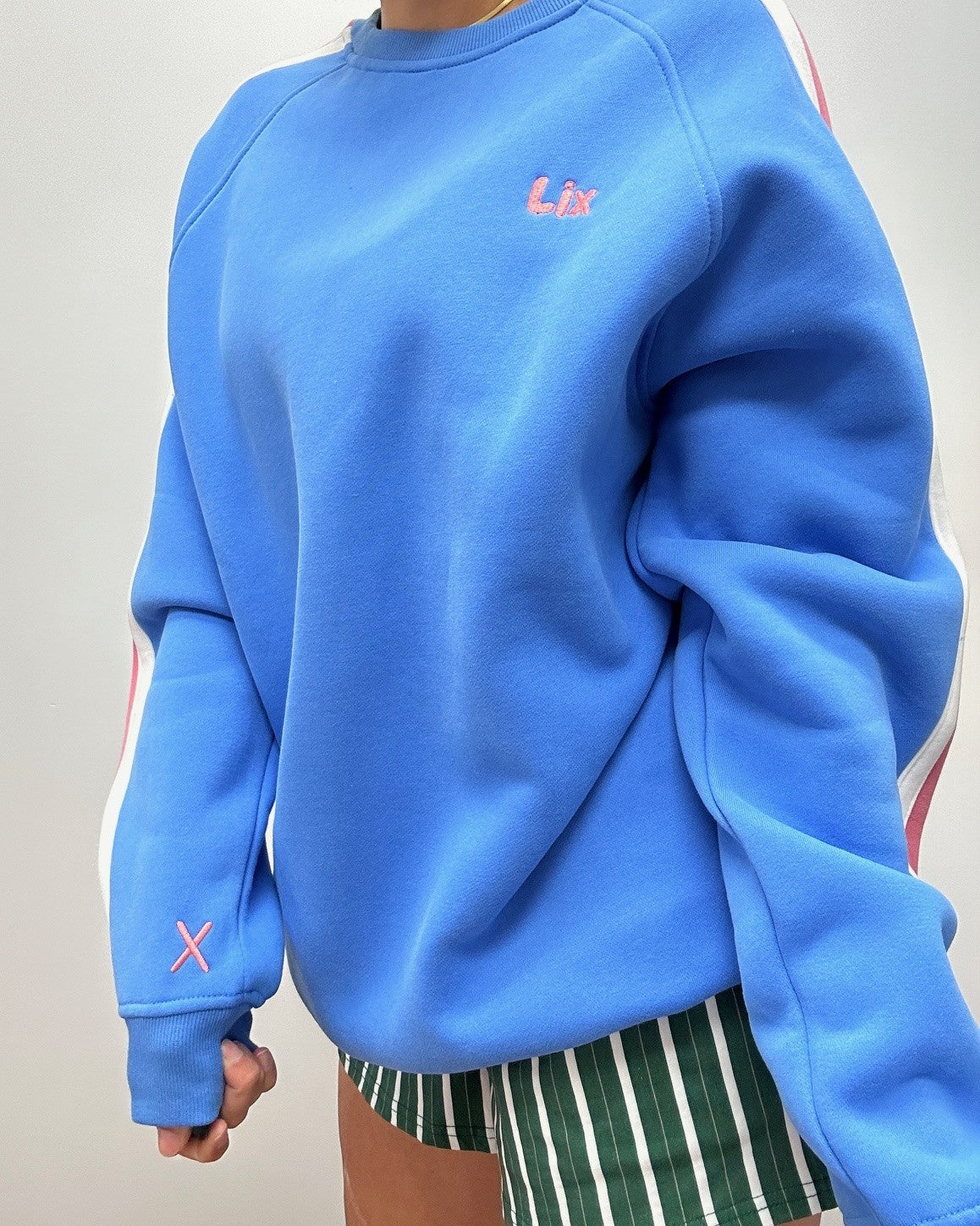 Crewneck bleu avec broderie rose, rayure rose et blanche sur les manches. Style vintage année 90. Short verte rayé blanche et brune