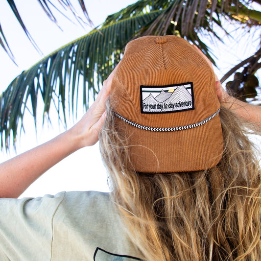 Casquette brune en corduroy avec corde rayée noire et blanche. Badge blanche avec design for your day to day adventure. Casquette non structuré brune.