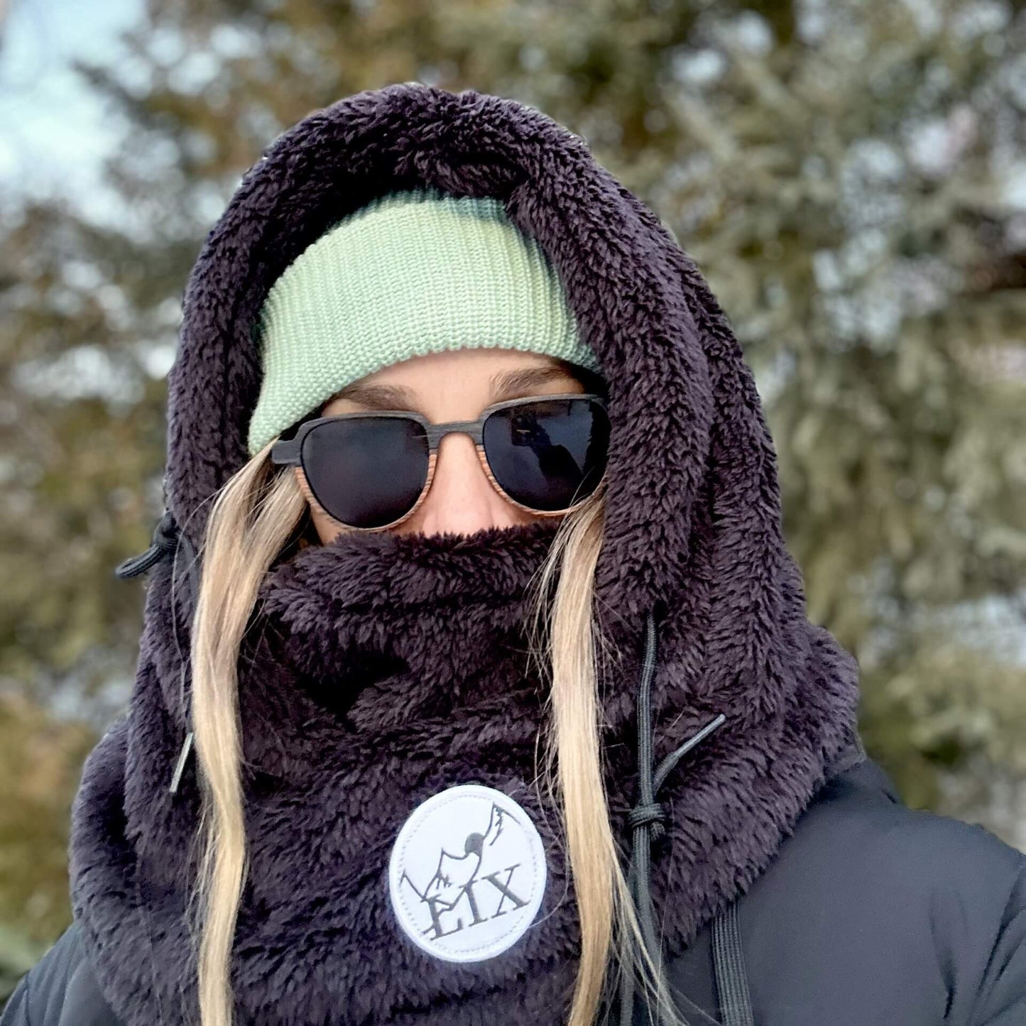 Rider hood de couleur noir avec capuche ajustable et cache-cou intégré. Mountain hood noir par dessus casque de ski.