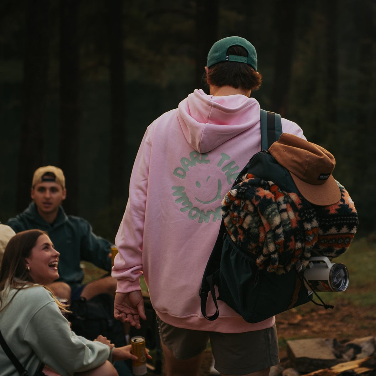 Hoodie de couleur rose avec bonhomme sourire à l'arrière de couleur vert. Inscription Dare The Unknown au dos. Chandail rose épais et lourd avec capuche.  Sac à dos vert recyclé. Sac d'école Lavoie.  Passenger clothing backpack. Herschel backpack. best backpack for camping. Backpack made in canada. Lix. Sac a dos Canada