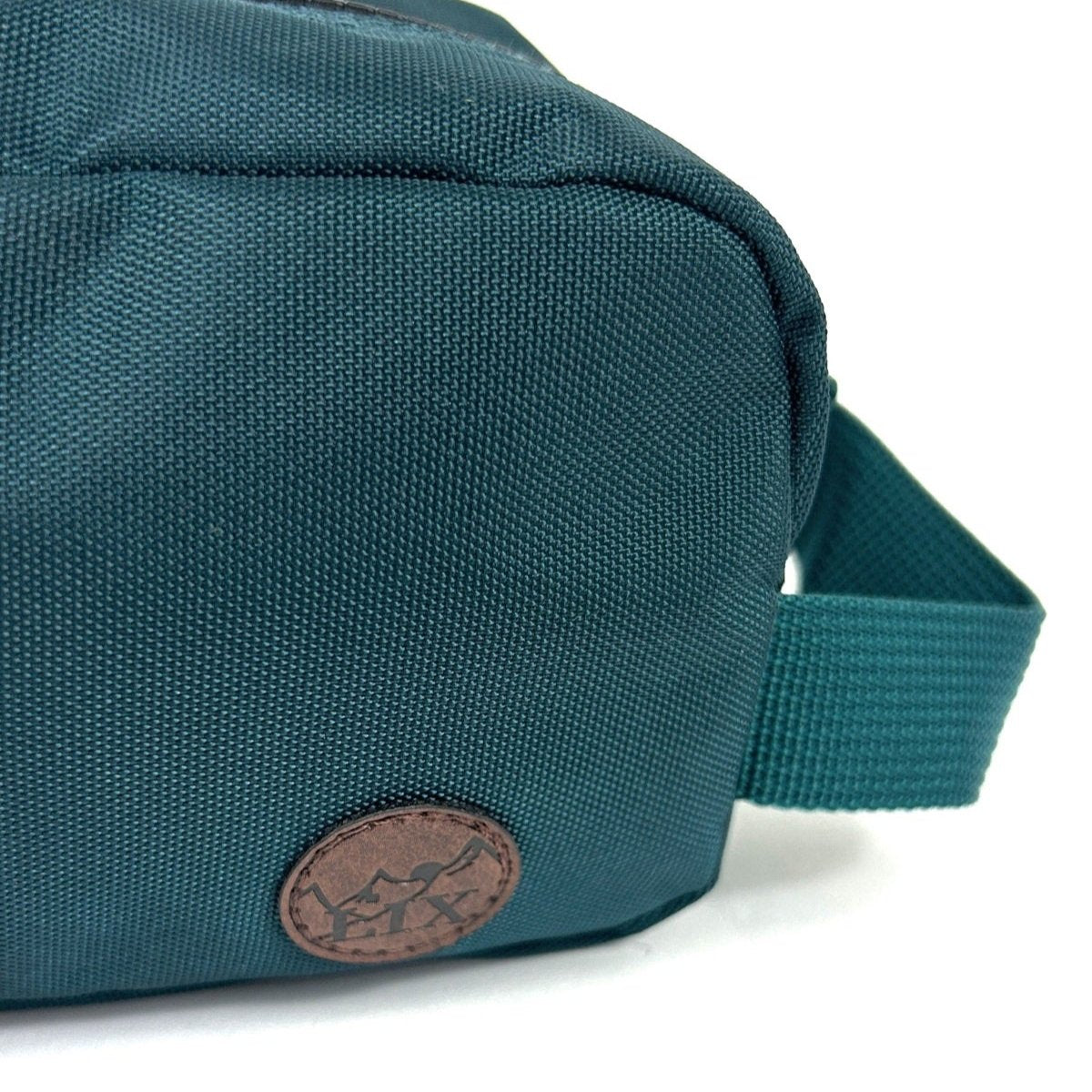 Trousse de voyage de couleur verte émeraude conçu par Lix design une entreprise québécoise. Fais de matières recyclées, de bouteilles de plastique post consommation. Avec logo embossé dans un badge en cuir synthétique de couleur brune. Sangle pour le transport.