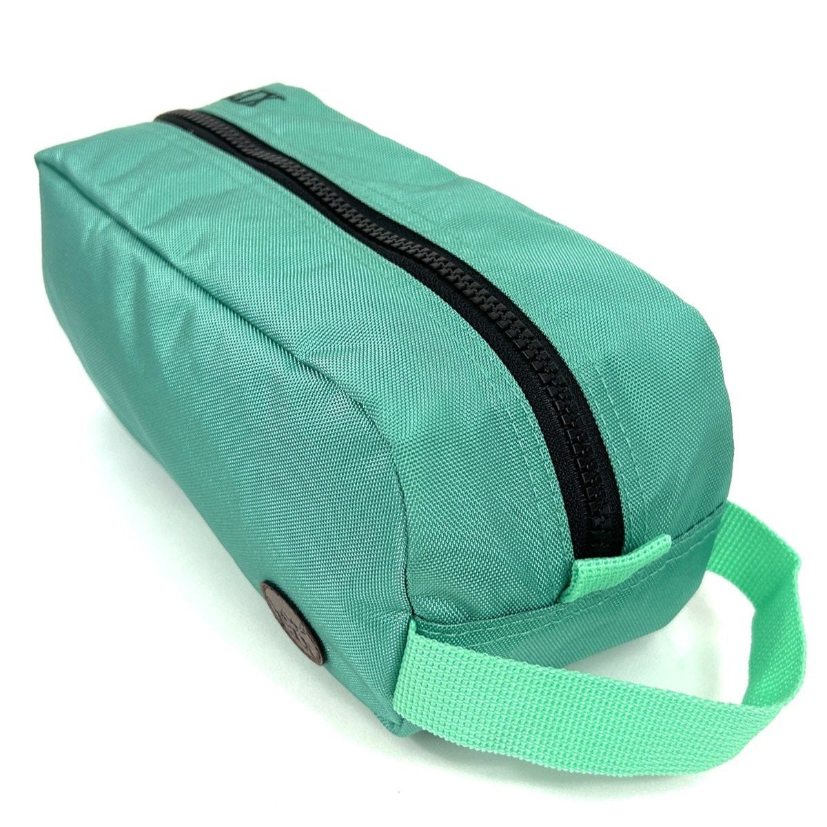 Trousse de voyage de couleur bleue turquoise conçu par Lix design une entreprise québécoise. Fais de matières recyclées, de bouteilles de plastique post consommation. Avec logo embossé dans un badge en cuir synthétique de couleur brune. Lix brodé en noir sur le dessus. Durable et écoresponsable.