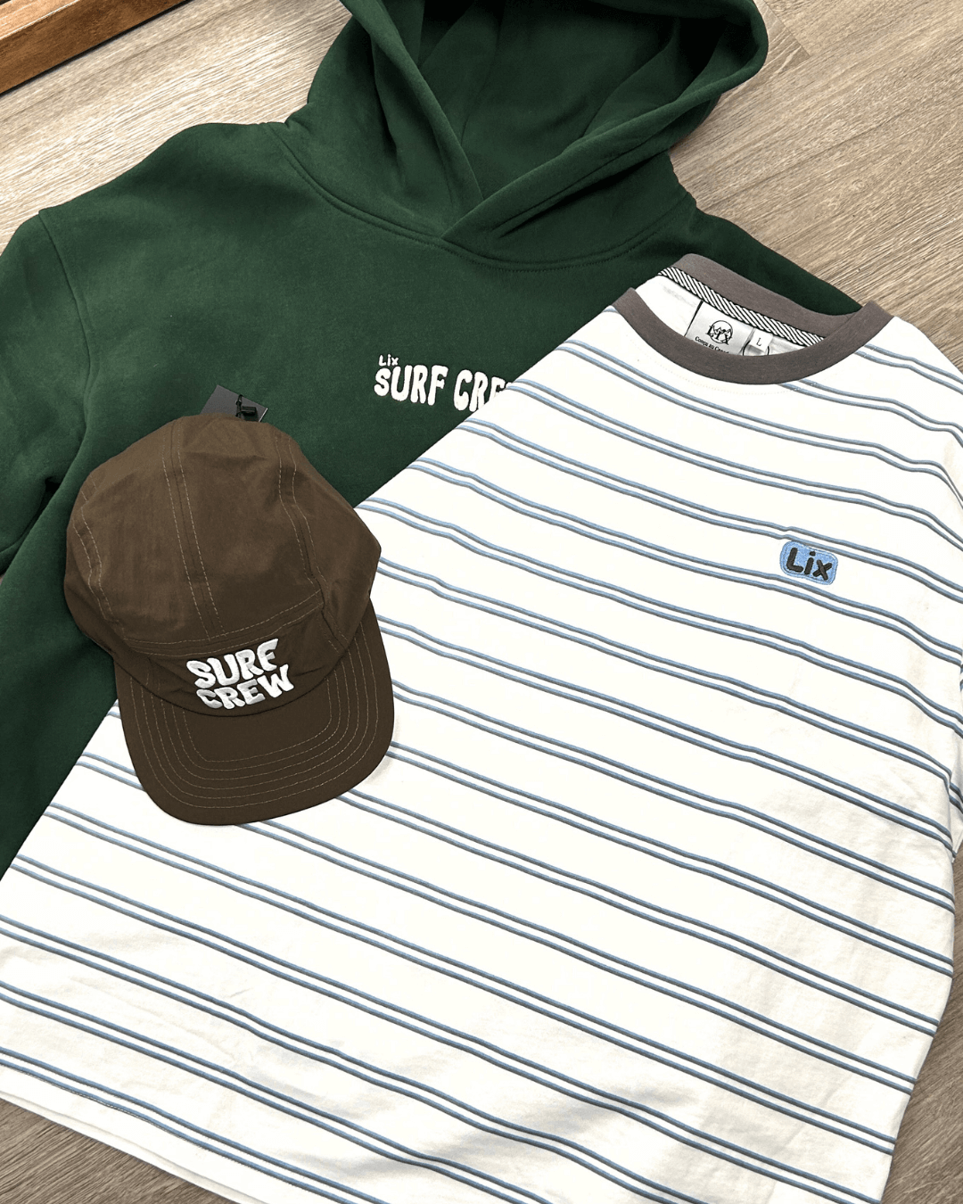 Set tshirt blanc rayé bleu et brun avec col brun jumelé avec notre hoodie vert forêt et broderie surf crew blanche et une casquette brune avec brodeir blanche surf crew. 