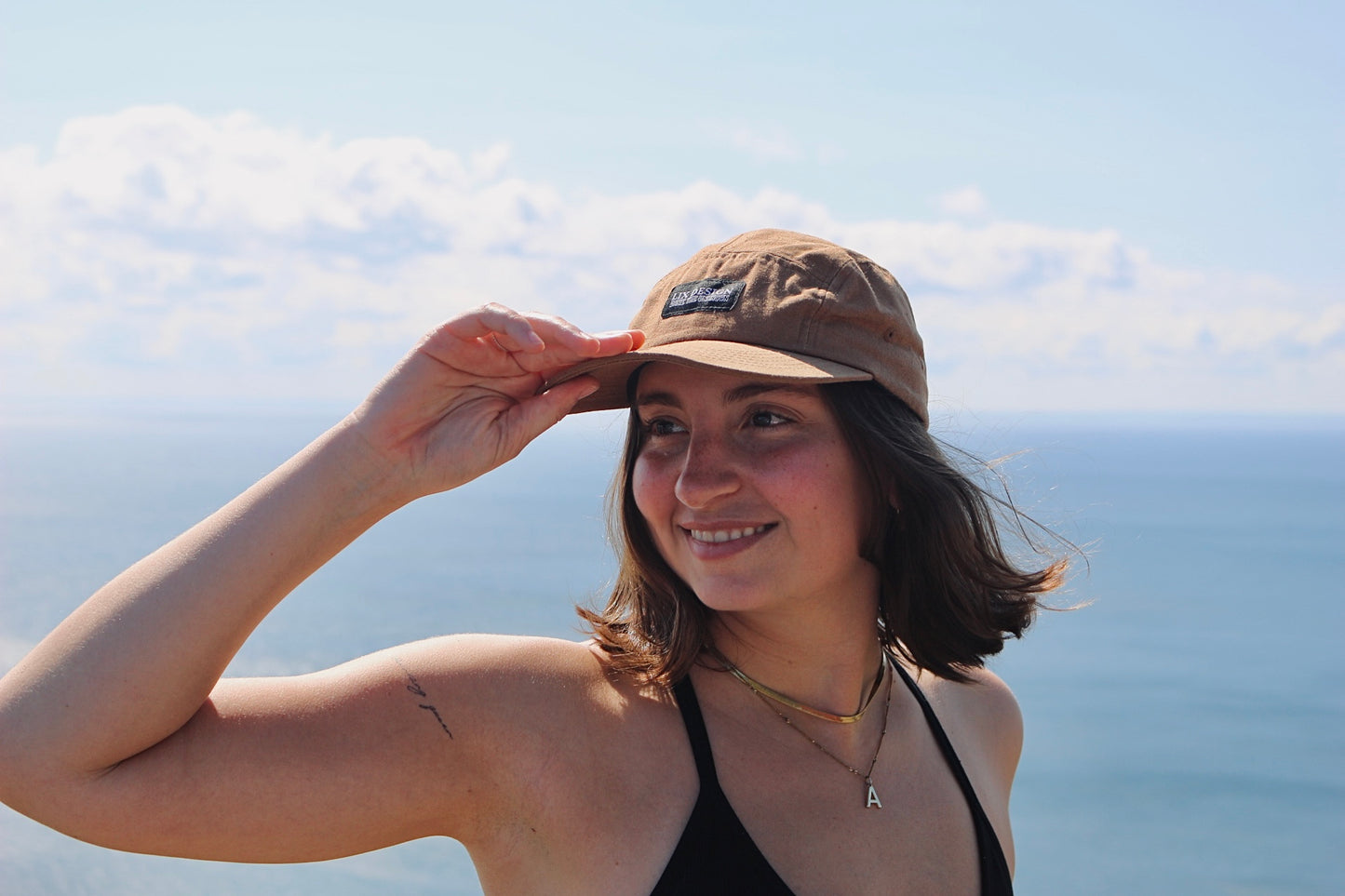 Casquette brune avec étiquette noir. Casquette à 5 panneaux avec visière droite pouvant être courbé.  Casquette de trek.