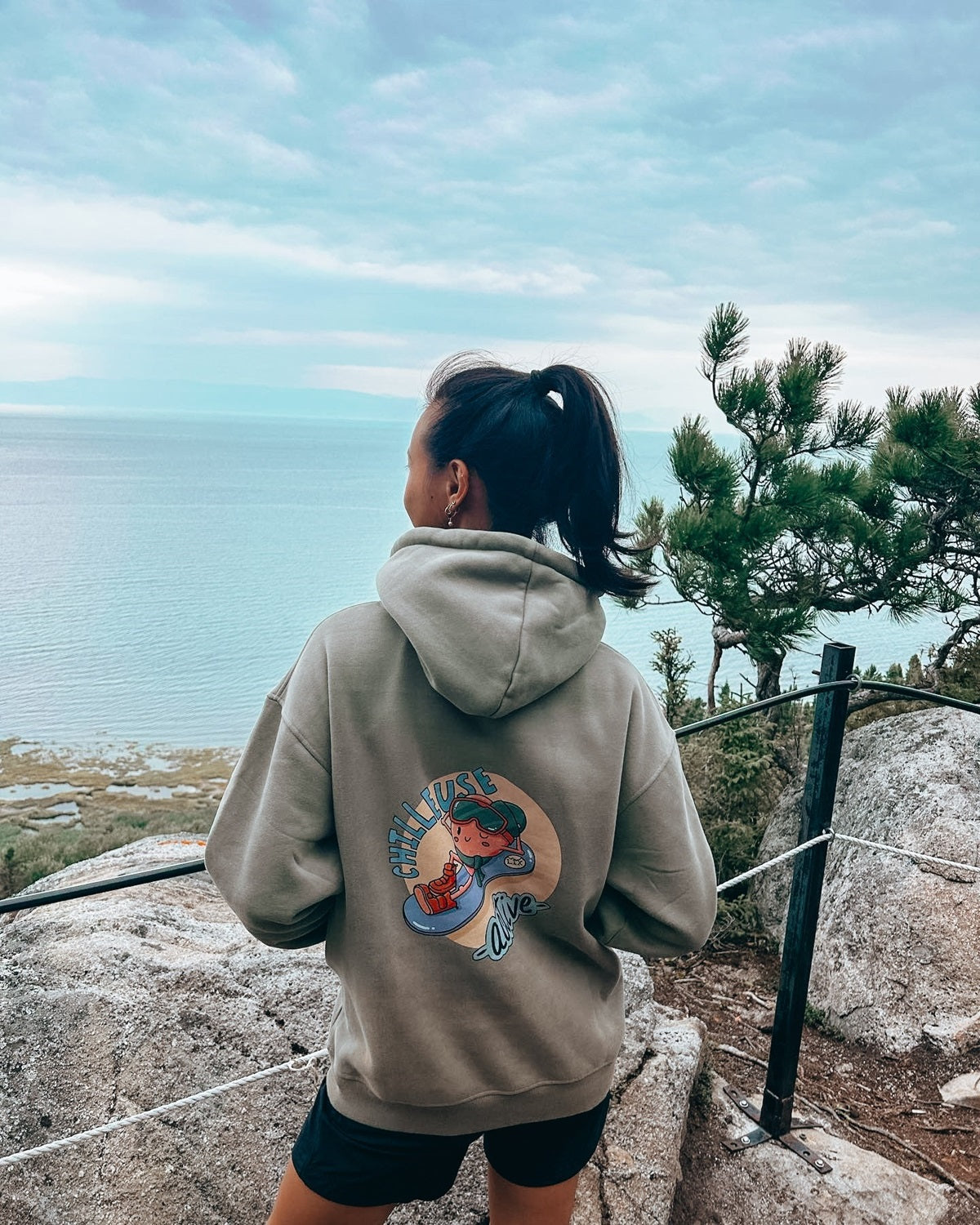 Hoodie vert exclusif en collaboration avec l'illustratrice Jade Lachine. Dessin chilleuse active avec une fraise qui descend une pente de ski sur un snowboard en relaxant. Fit oversize.