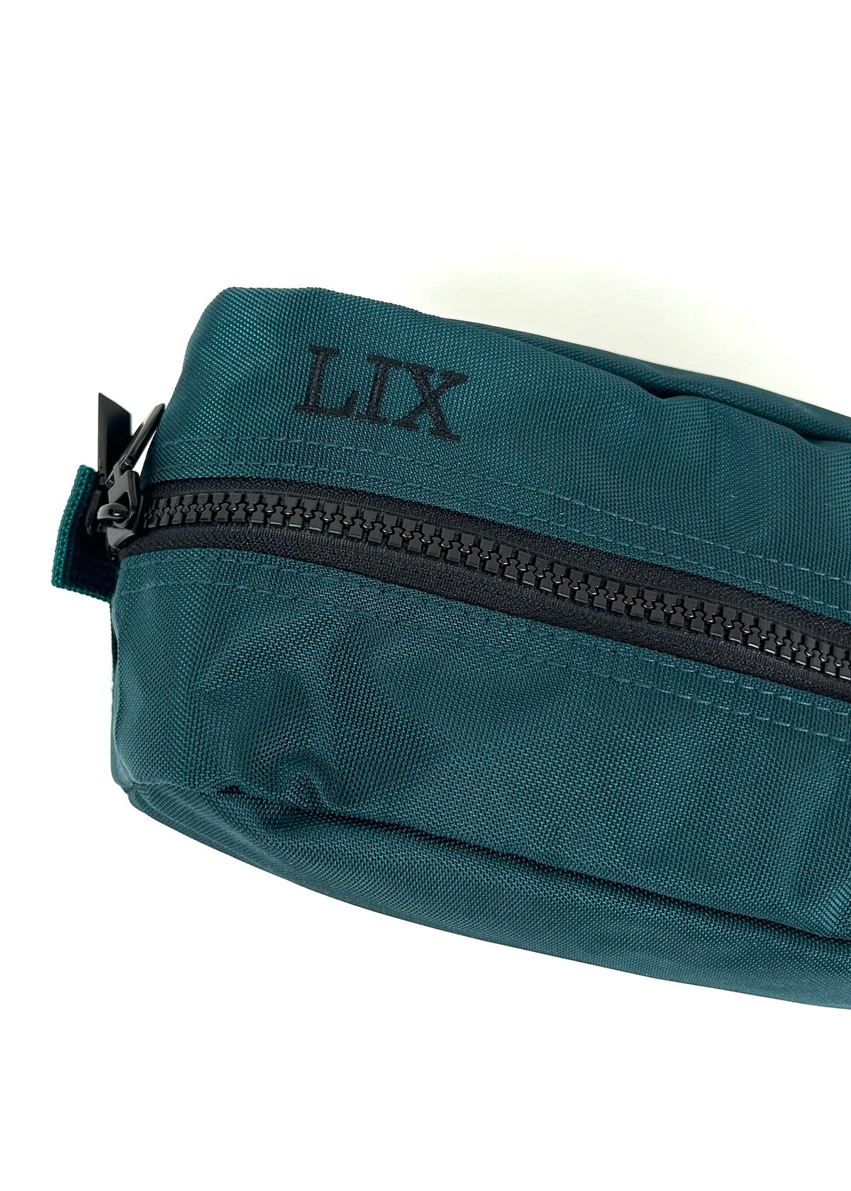 Trousse de voyage de couleur verte émeraude conçu par Lix design une entreprise québécoise. Fais de matières recyclées, de bouteilles de plastique post consommation. Avec logo embossé dans un badge en cuir synthétique de couleur brune. Lix brodé en noir sur le dessus. Durable et écoresponsable.  