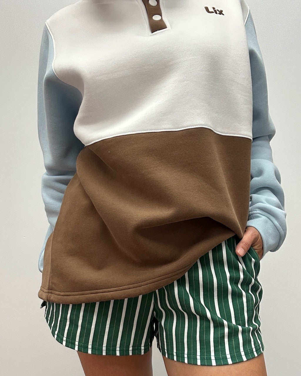 Crewneck colorblock avec ajustement à la taille pour femme blanc bleu brun et bouton pression au col. Concu par lix une entreprise québécoise. 