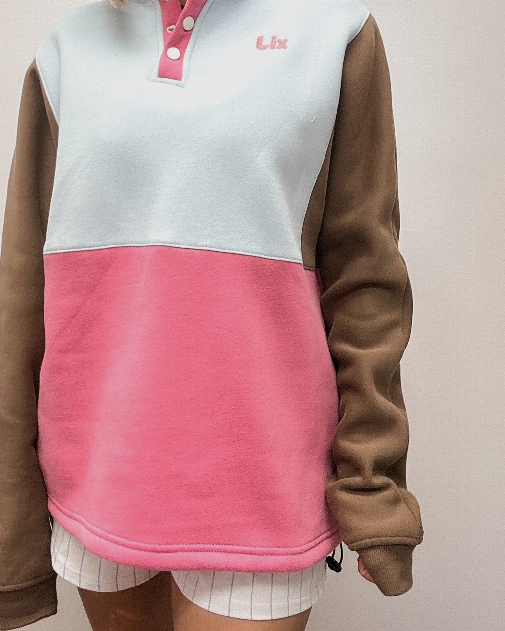 Crewneck rose bleu et brun ajustable à la taille. Bouton pression au col. Conçu au Québec pour les femmes de 25-45 ans qui voyagent. 