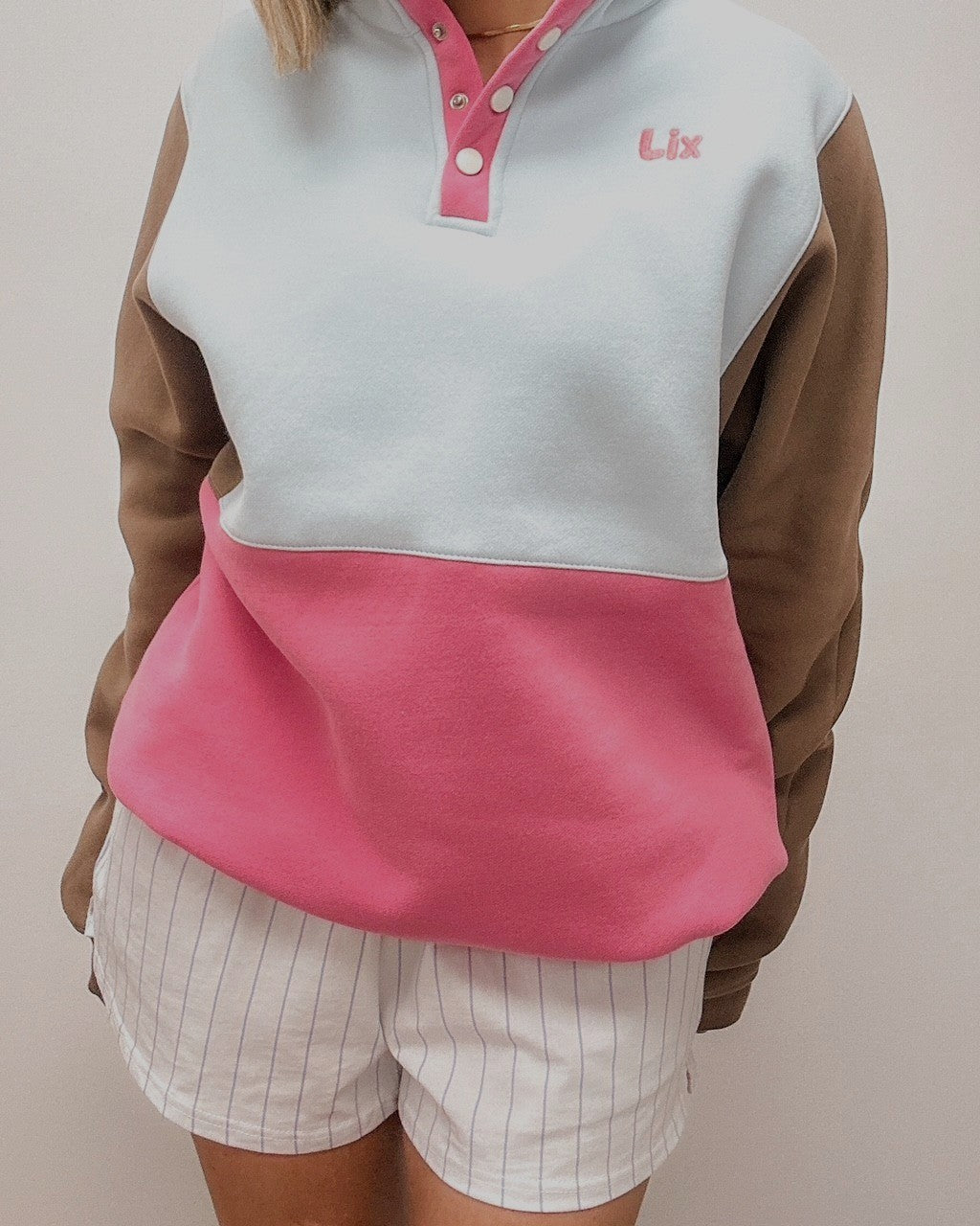 Outfit de style vintage année 90 pour femme avec short en coton blanche rayé bleu et crewneck colorblock rose bleu et brun ajustable à la taille. 