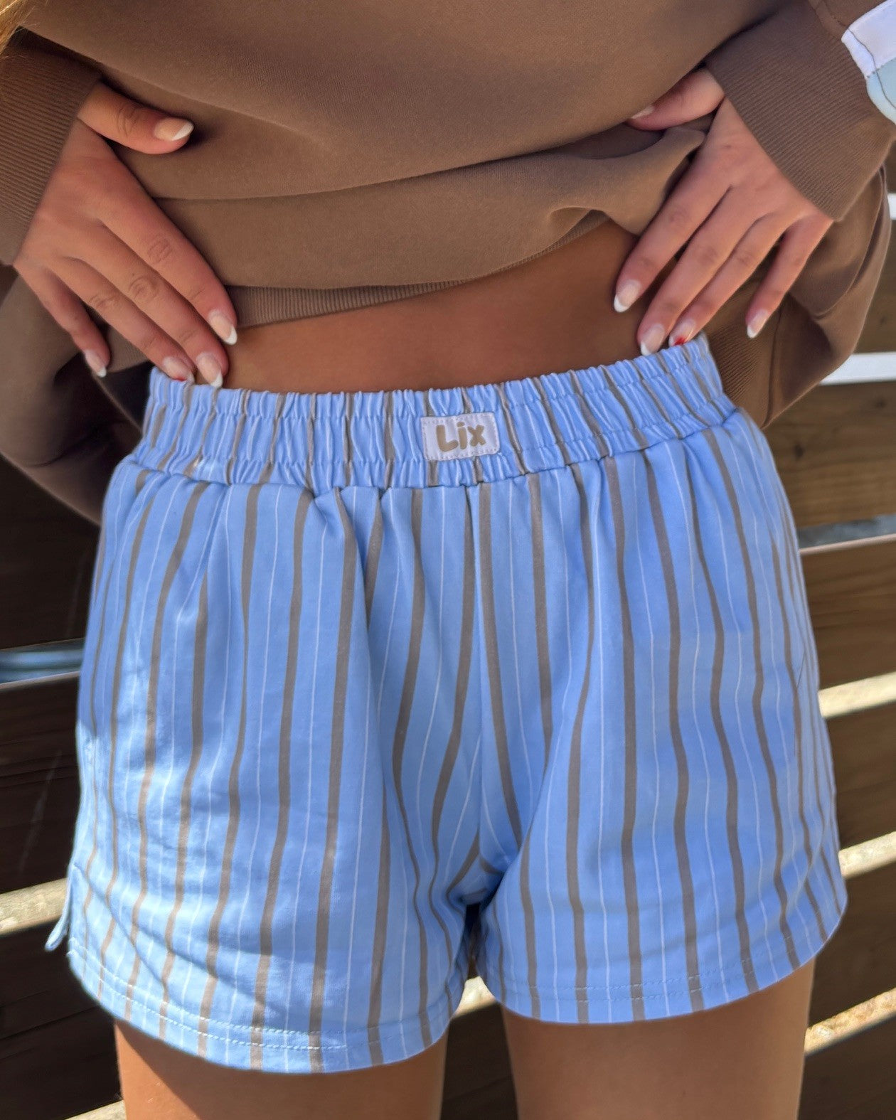 Short en coton bleu avec étiquette lix blanche au devant. Rayure brune et blanche pour un look summer vibe chill avec un style vintage année 90.  