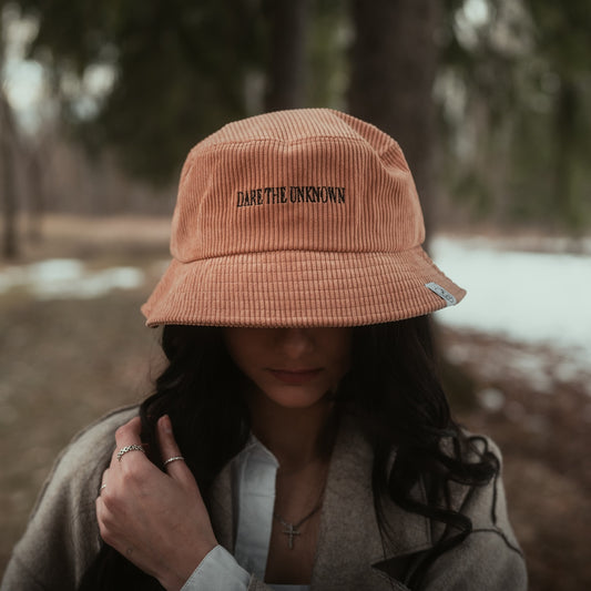 Chapeau de style bob hat fait de matières recyclées. Conçu par Lix design une entreprise Québécoise.  Fabriqué en corduroy de couleur orange avec l'inscription dare the unknown en noir. 