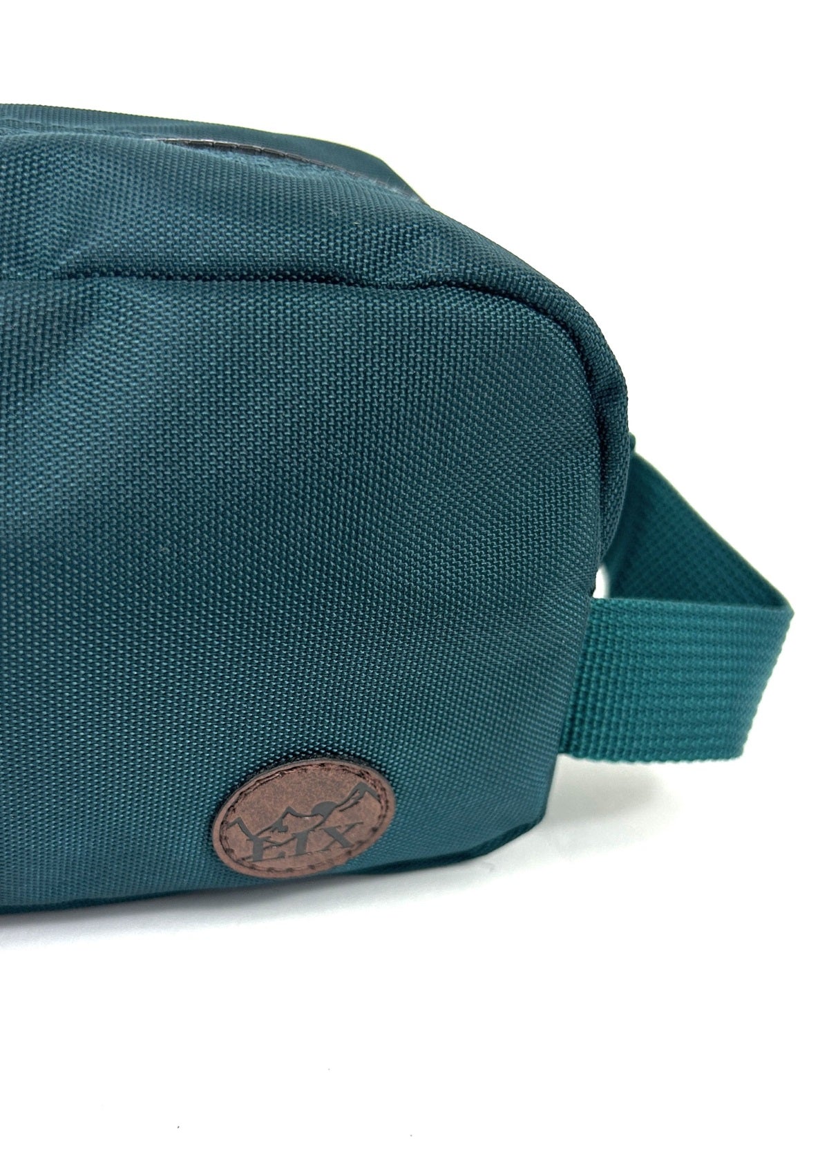 Trousse de voyage de couleur verte émeraude conçu par Lix design une entreprise québécoise. Fais de matières recyclées, de bouteilles de plastique post consommation. Avec logo embossé dans un badge en cuir synthétique de couleur brune. Sangle pour le transport. 